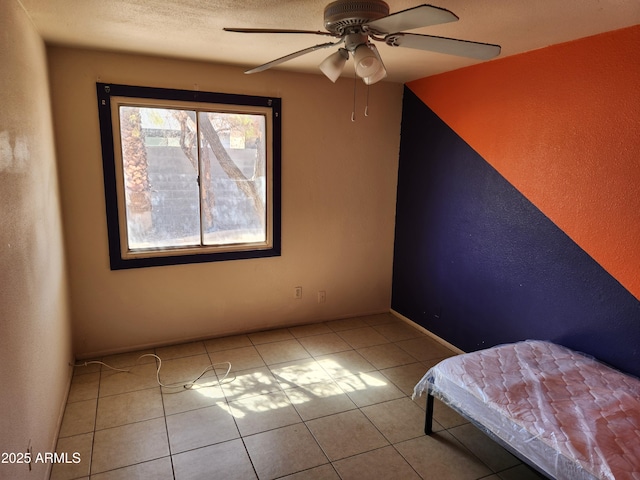 unfurnished bedroom featuring ceiling fan, a textured ceiling, and tile patterned flooring