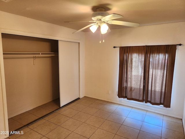 unfurnished bedroom with light tile patterned floors, ceiling fan, and a closet