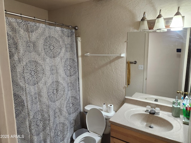 bathroom featuring toilet, vanity, a shower with shower curtain, and a textured wall