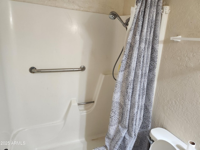 full bath with toilet, a textured wall, and a shower with shower curtain