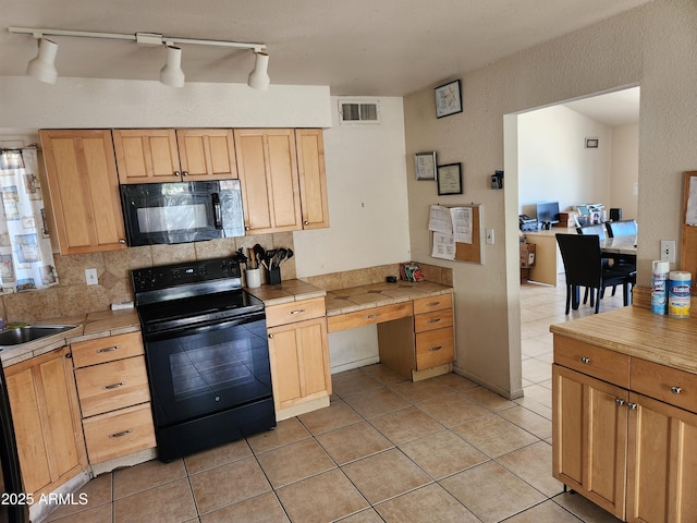 kitchen with tile counters, visible vents, backsplash, a sink, and black appliances