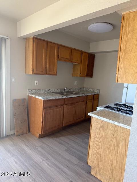 3840 N 43rd Ave Unit 16, Phoenix, AZ 85031 - kitchen featuring light wood finished floors, a sink, brown cabinets, and light countertops