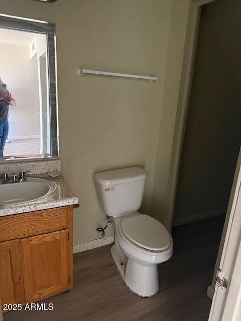 3840 N 43rd Ave Unit 16, Phoenix, AZ 85031 - half bathroom with baseboards, wood finished floors, toilet, and vanity