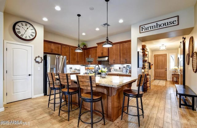 707 Lunar View Way, Chino Valley, AZ 86323 - kitchen featuring under cabinet range hood, light wood finished floors, light stone counters, a breakfast bar, and recessed lighting
