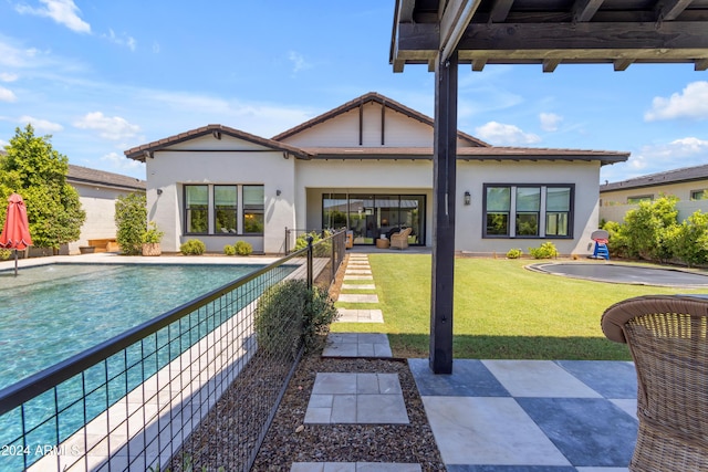 rear view of house with a fenced in pool, a patio area, and a lawn