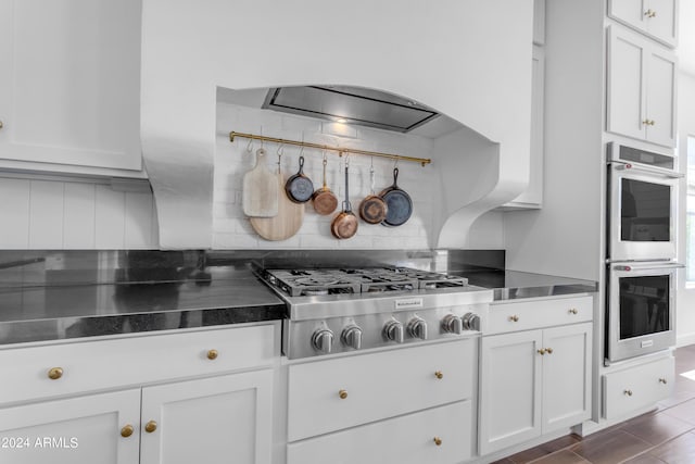 kitchen with white cabinetry, backsplash, stainless steel counters, and stainless steel appliances