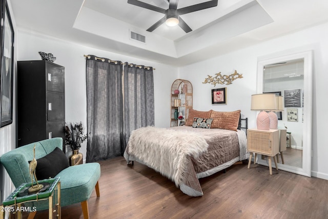 bedroom featuring dark wood-type flooring, ceiling fan, and a raised ceiling