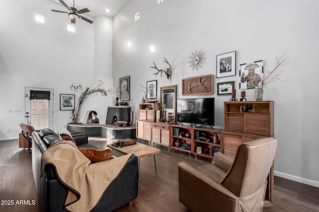 living room featuring a high ceiling, dark wood-type flooring, and ceiling fan