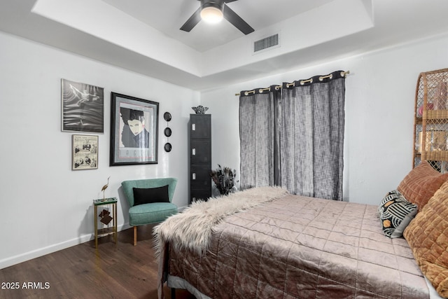 bedroom with wood-type flooring, a raised ceiling, and ceiling fan