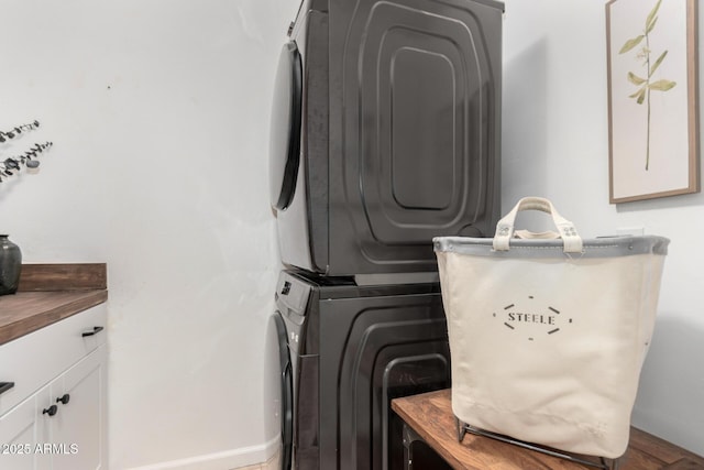 clothes washing area featuring cabinets, stacked washer / dryer, and hardwood / wood-style floors