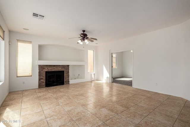 unfurnished living room featuring a healthy amount of sunlight, light tile patterned floors, a ceiling fan, and visible vents