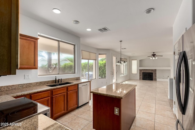 kitchen featuring brown cabinets, ceiling fan, a sink, stainless steel appliances, and visible vents