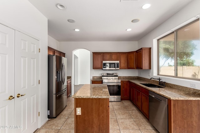 kitchen with arched walkways, a center island, a sink, stainless steel appliances, and recessed lighting