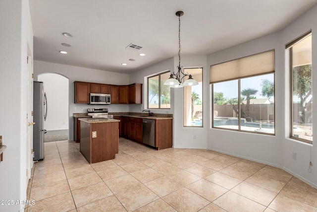 kitchen with visible vents, light tile patterned flooring, a kitchen island, a sink, and stainless steel appliances