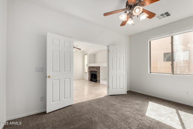 unfurnished bedroom with a stone fireplace, visible vents, tile patterned flooring, baseboards, and carpet flooring