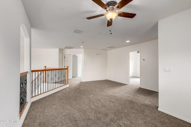 empty room with arched walkways, carpet, a ceiling fan, and visible vents