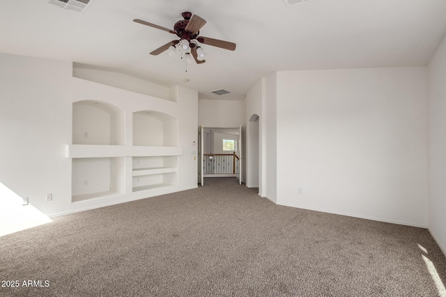 carpeted spare room featuring baseboards, a ceiling fan, built in shelves, and visible vents