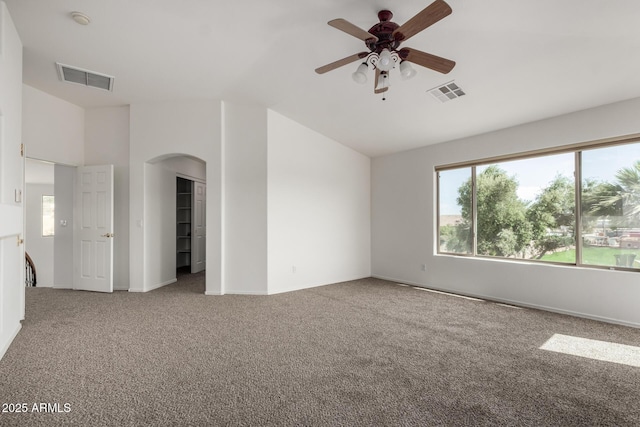 carpeted spare room with arched walkways, ceiling fan, visible vents, and vaulted ceiling