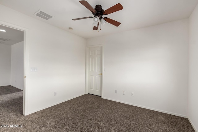 unfurnished room with baseboards, a ceiling fan, dark carpet, and visible vents