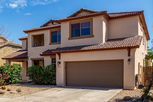 mediterranean / spanish house with a tiled roof, stucco siding, and a garage