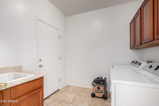 washroom with a sink, light tile patterned flooring, cabinet space, and washing machine and clothes dryer