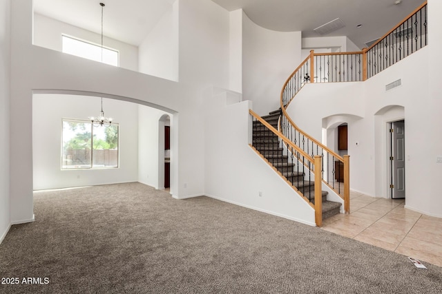 unfurnished living room featuring carpet flooring, a high ceiling, an inviting chandelier, and a wealth of natural light