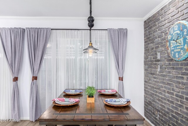 dining room with hardwood / wood-style flooring, crown molding, and brick wall