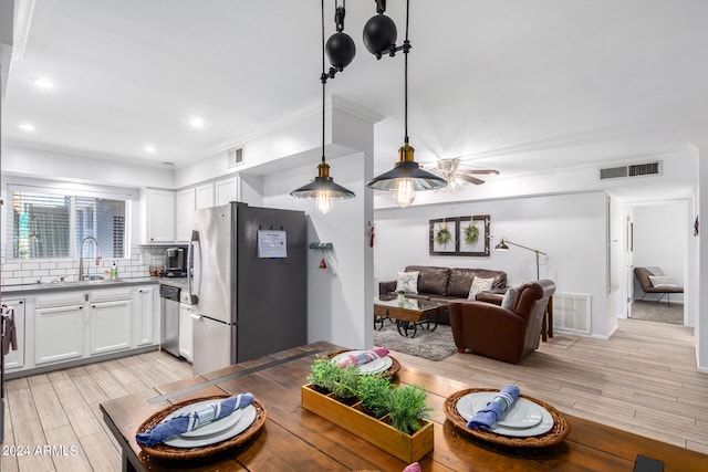 dining room with light wood-type flooring, crown molding, and sink