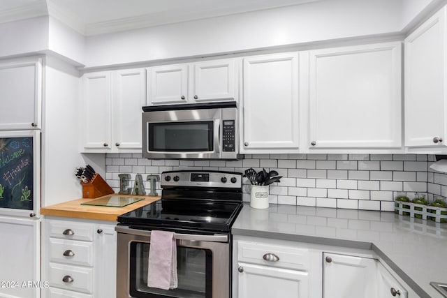 kitchen with crown molding, appliances with stainless steel finishes, white cabinets, and decorative backsplash