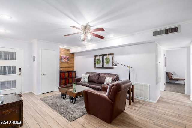 living room with ornamental molding, wood walls, ceiling fan, and light hardwood / wood-style floors