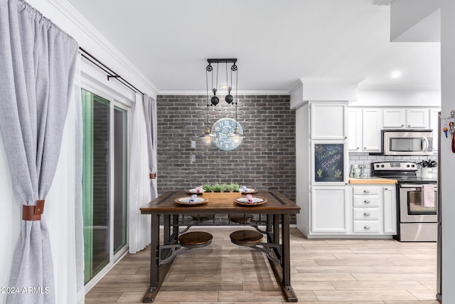 kitchen featuring crown molding, white cabinetry, light hardwood / wood-style flooring, stainless steel appliances, and hanging light fixtures