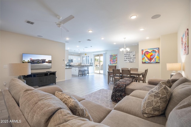 living room with ceiling fan with notable chandelier