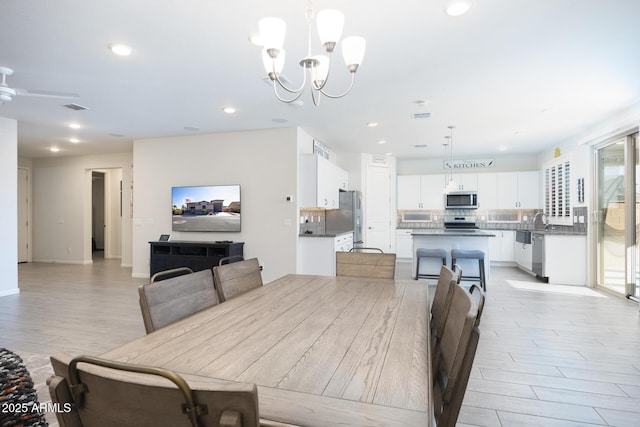 dining space with light hardwood / wood-style floors, sink, and a notable chandelier