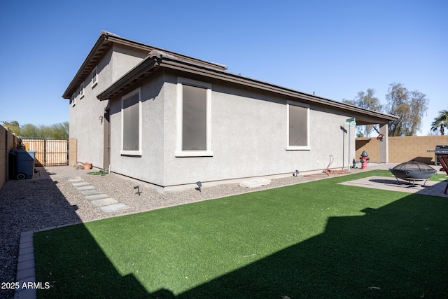 rear view of property with a patio area, an outdoor fire pit, and a lawn