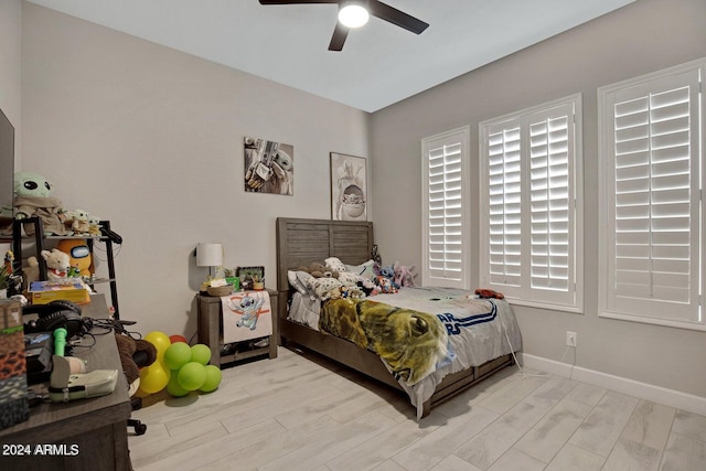 bedroom with light wood-style flooring, a ceiling fan, and baseboards