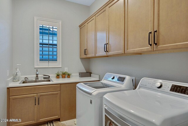 laundry room with sink, washing machine and dryer, and cabinets