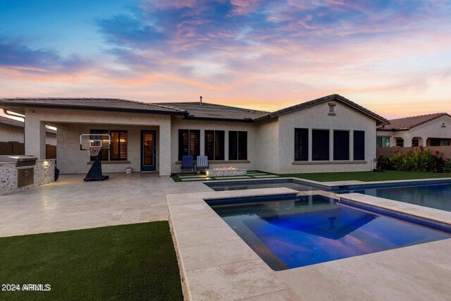 back house at dusk featuring a patio area, area for grilling, and a swimming pool with hot tub