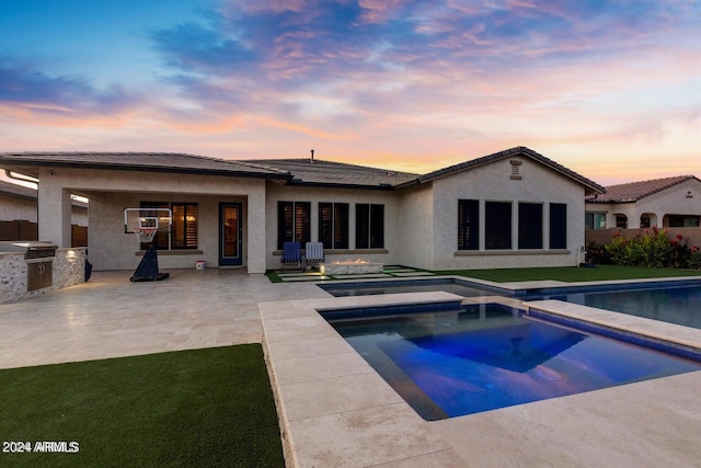 back of house featuring stucco siding, an outdoor pool, exterior kitchen, and a patio