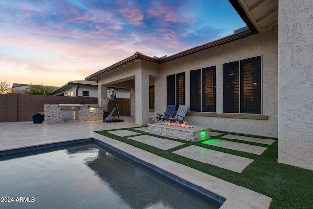 view of swimming pool featuring area for grilling, a patio, fence, an outdoor fire pit, and exterior kitchen