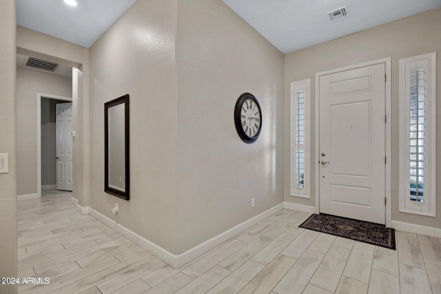 entrance foyer with visible vents, baseboards, and wood finish floors