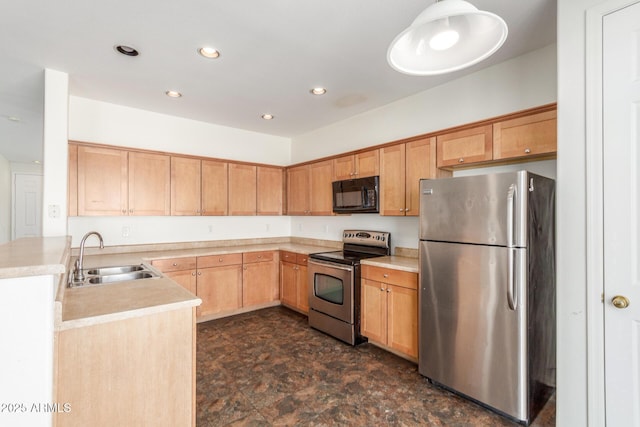 kitchen with recessed lighting, a sink, light countertops, appliances with stainless steel finishes, and stone finish flooring