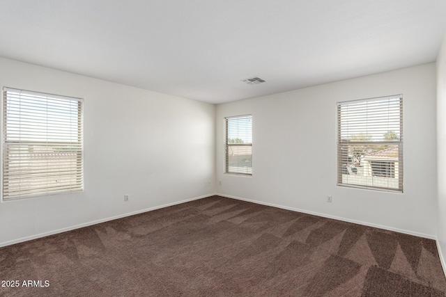 spare room featuring carpet flooring, visible vents, and baseboards