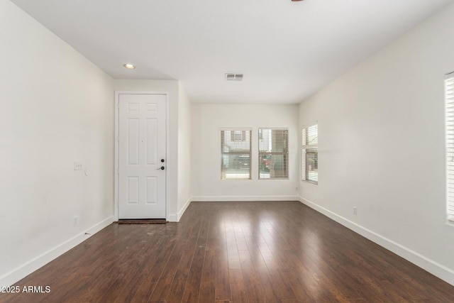 spare room featuring dark wood-style floors, visible vents, and baseboards