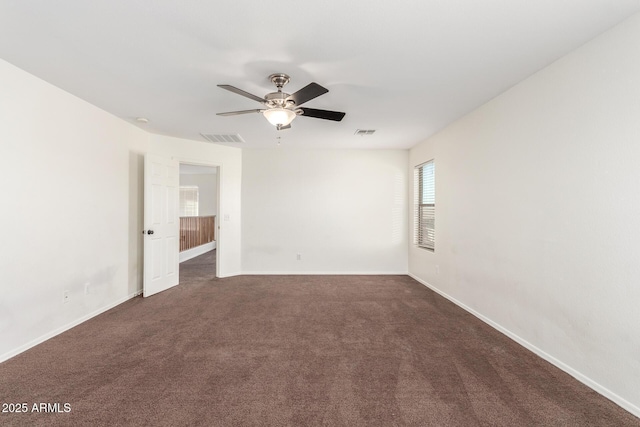 spare room featuring ceiling fan, dark carpet, visible vents, and baseboards