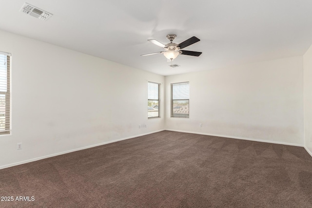 spare room with visible vents, dark carpet, baseboards, and ceiling fan