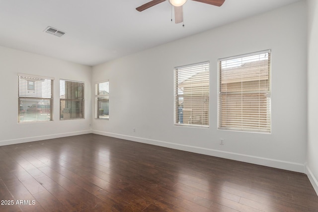 empty room with dark wood-style floors, baseboards, visible vents, and ceiling fan