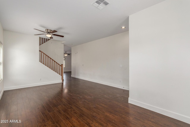 unfurnished living room featuring dark wood-style flooring, visible vents, baseboards, a ceiling fan, and stairway