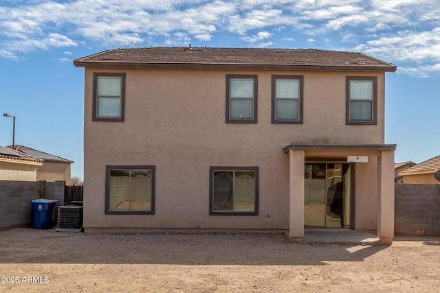 back of property with fence, central AC, and stucco siding