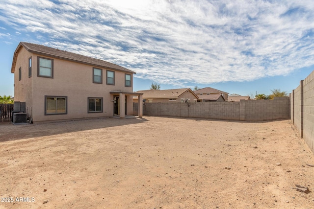 back of house with stucco siding, a fenced backyard, and central air condition unit