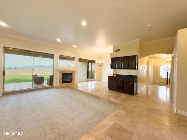 unfurnished living room featuring crown molding and a chandelier